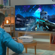 A man in a living room uses the Optoma UHD35STx to play video games on a screen.